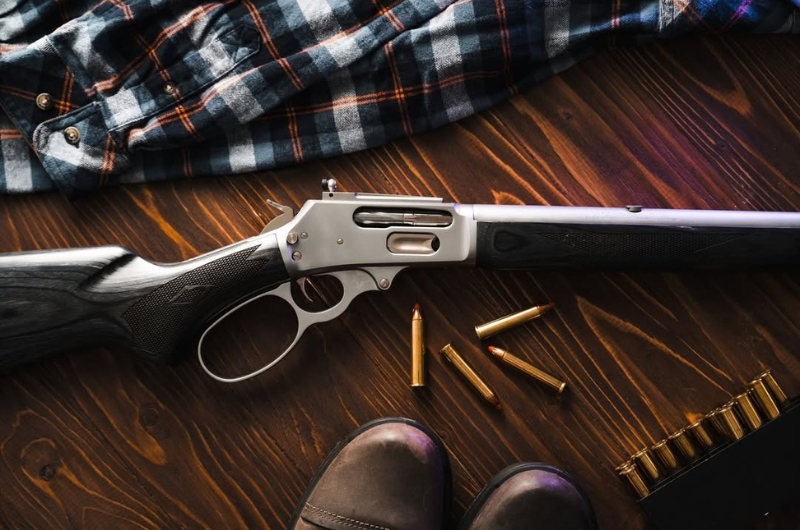 Rifle de palanca MARLIN 1895 Trapper con munición sobre fondo de madera