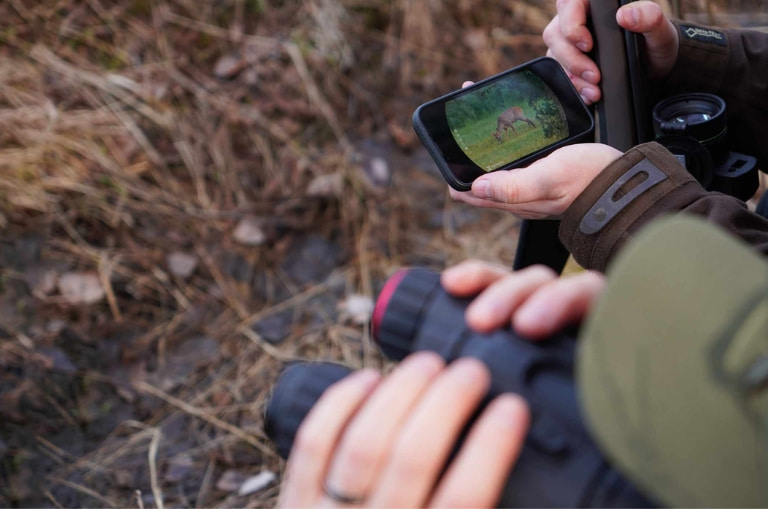 Persona conectando un binocular HIKMICRO HABROK al móvil para ver imagen térmica en el campo