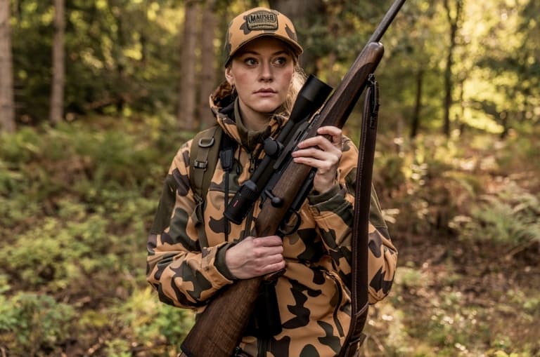 Cazadora con rifle Mauser M25 Pure y visor en el bosque